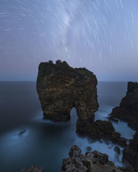 Rock formation in sea against sky at night