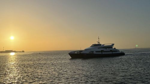 Ship sailing in sea against sky during sunset