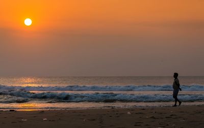 Full length of woman on beach against sky during sunset