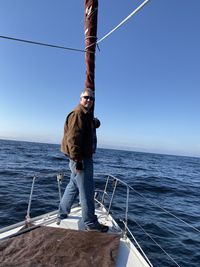 Man standing on boat in sea against sky