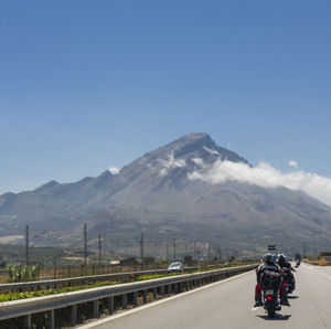 Man riding motorcycle on road against mountain range