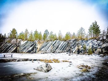 Stack of stones on snow covered landscape against sky