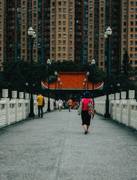 Rear view of people walking on street in city