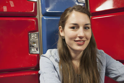 A young woman by some red and blue lockers.