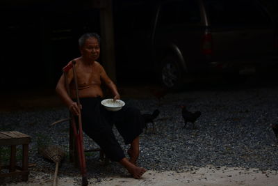 Full length of shirtless man having food at night