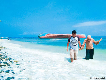 Rear view of men standing at beach against sky