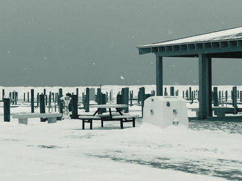 Snow covered field by building against sky