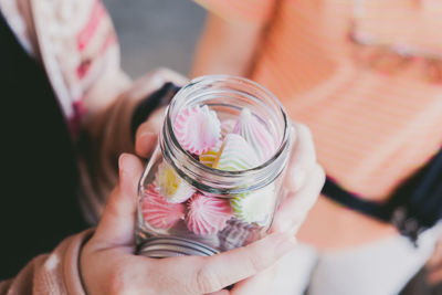 Midsection of woman holding glass jar