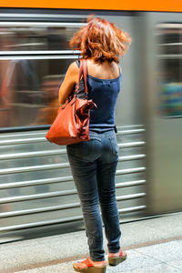 Rear view of woman standing at railroad station