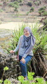 Portrait of smiling woman standing amidst plants