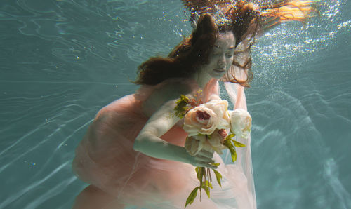Woman holding flowers while swimming in pool