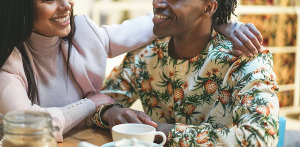 Midsection of smiling couple sitting in cafe