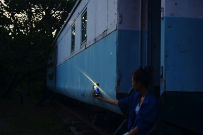 Rear view of woman sitting against blue train