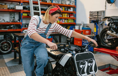 Mechanic woman starting custom motorcycle on factory