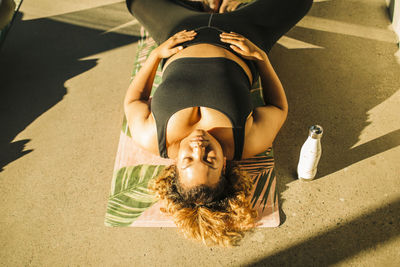 High angle view of woman exercising while lying on floor during yoga class