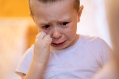 Little boy cries from grief and resentment. he wipes tears from his cheek with his hand.