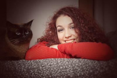 Portrait of smiling woman with cat on couch at home