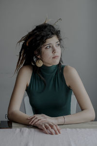 Portrait of woman sitting against wall