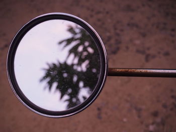 Mirror of a motorcycle in the shadow of a mirror has a tree