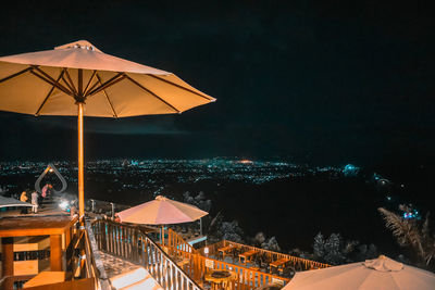 Chairs and tables at restaurant against sky at night