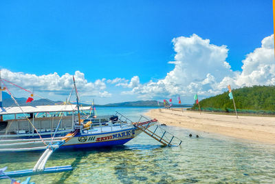 Sailboats moored on sea against blue sky