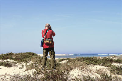 Rear view of woman standing on beach against sky