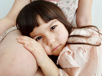 Close-up portrait of young woman lying on bed