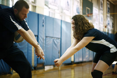 Coach teaching volleyball to teenage girl in court