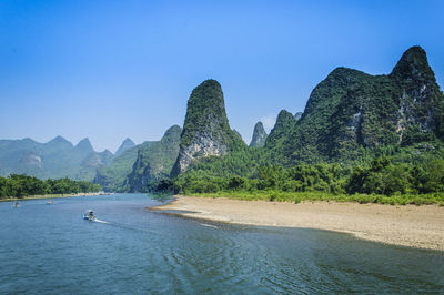 Scenic view of sea and mountains against clear sky