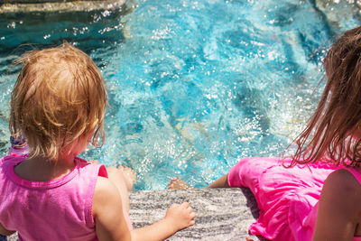 Rear view of mother and daughter in swimming pool