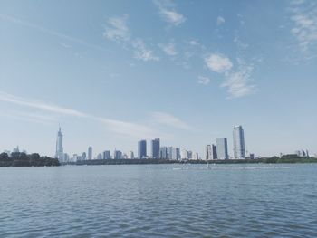 Sea by buildings in city against sky