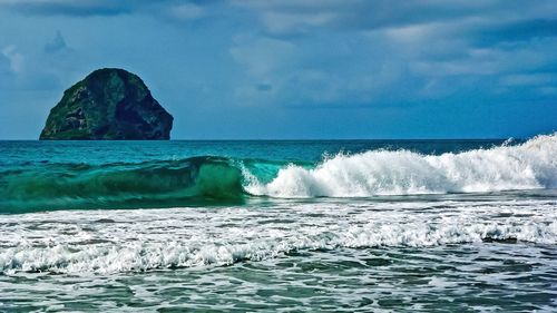 Scenic view of large rock in sea against sky