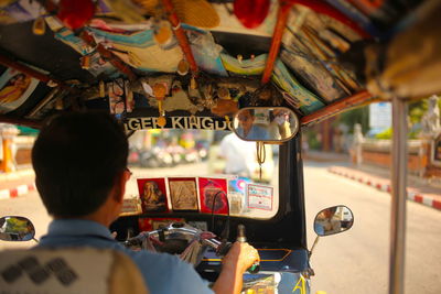 Rear view of tuk tuk driver with passenger