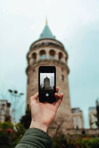Midsection of person holding smart phone against cathedral