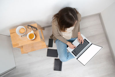 Unrecognizable woman sitting on floor and working on a laptop. female typing on notebook keyboard.