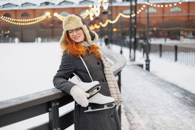 Portrait of young woman standing against railing