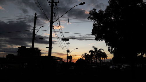 Low angle view of electricity pylon against cloudy sky