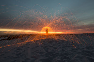 Light trails on beach against sky at night