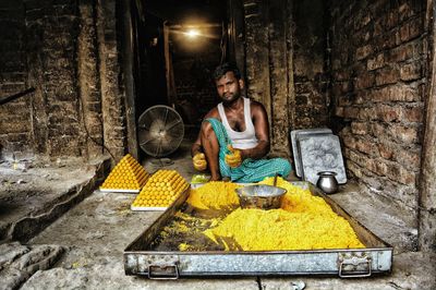 Portrait of mid adult man making sweet food while sitting at workshop