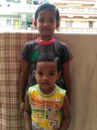 Portrait of cute brothers standing against fabric in balcony