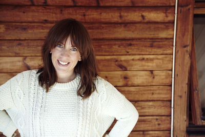 Smiling mid adult woman against wooden wall