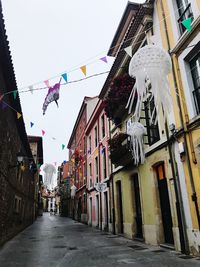 Multi colored flags hanging on building in city against sky