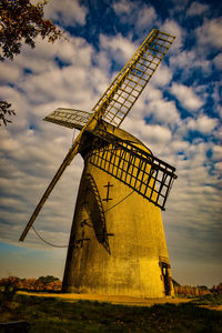 Low angle view of traditional windmill on field against sky