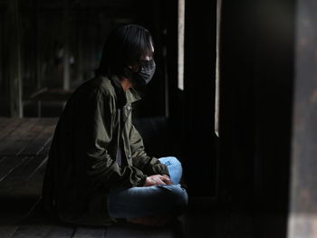 Side view of young man sitting at home