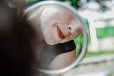 Cropped image of woman with red lipstick reflecting on mirror