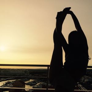 Silhouette woman practicing gymnastics in balcony against sky