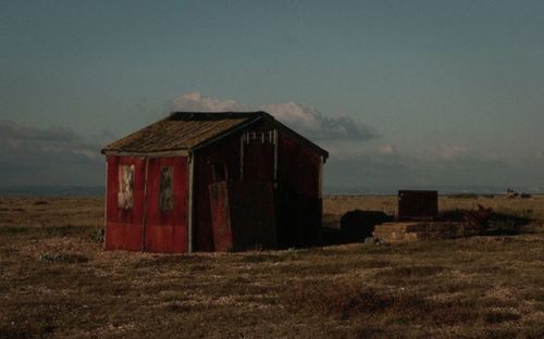 House on field against cloudy sky