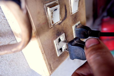 Cropped hand of person holding plug by socket