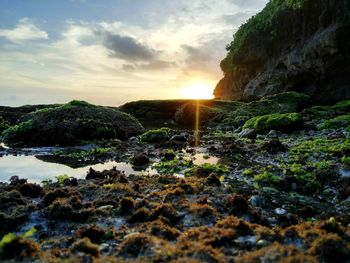 Rock formation by sea against sky during sunset