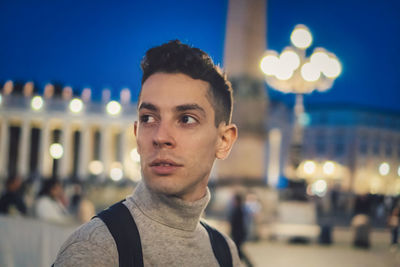 Portrait of man against illuminated city at night